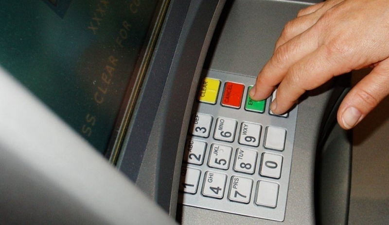 Ruka zadávající pin na bankomatu 