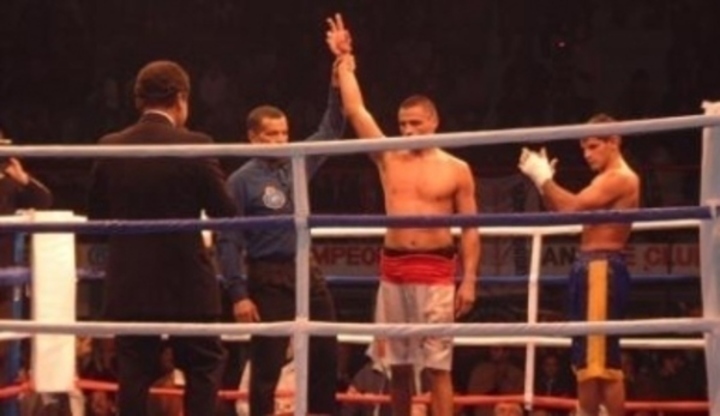 Rozhodčí v ringu zvedá vítězi boxu ruku