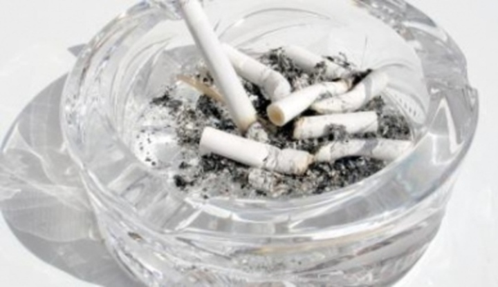 Skleněný popelník plný nedopalků cigaret