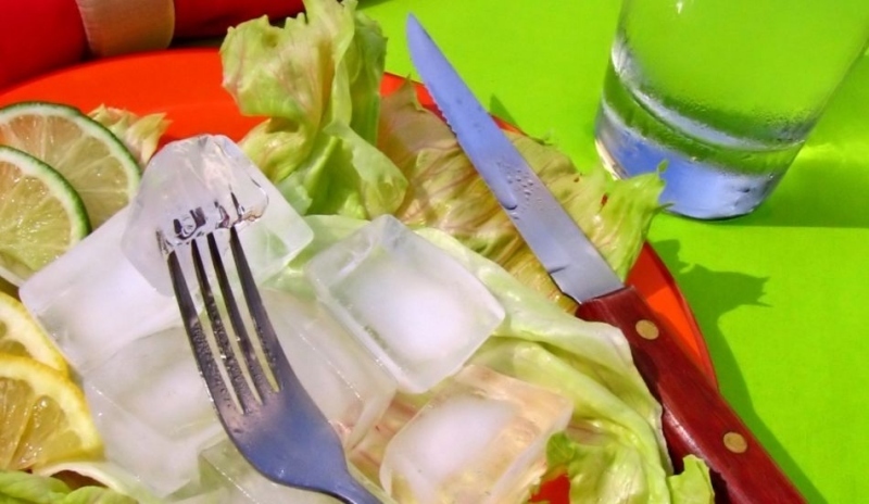 Kebab na listech salátu a položeným příborem 
