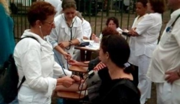 Zdravotnice měřící tlak sedícím osobám 
