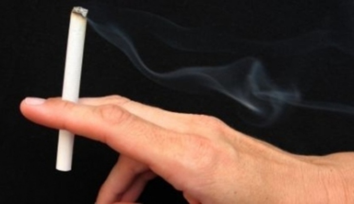Prsty držící zapálenou cigaretu 