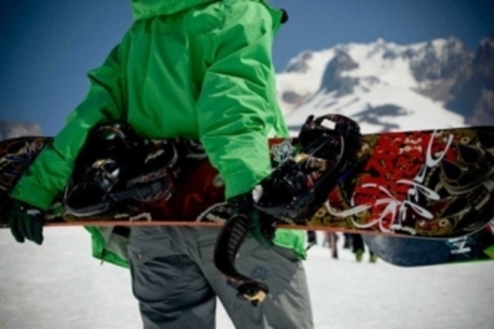 Muž držící snowboard za zády 
