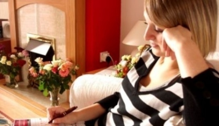 Žena sedí na pohovce s opřenou hlavou o ruku 