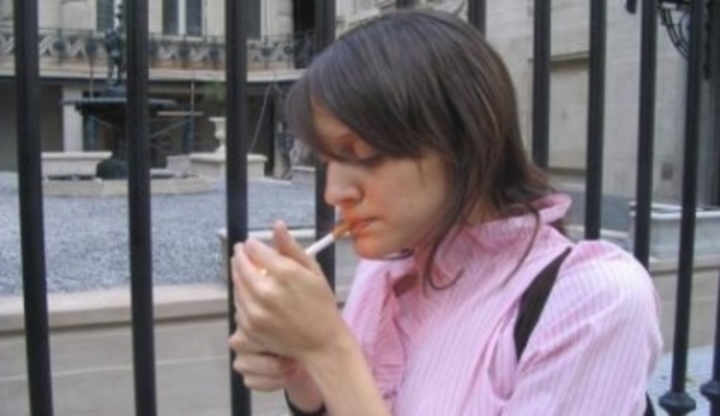 Žena zapalující si cigaretu