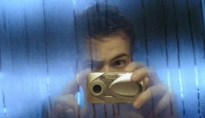 Muž za sklem s digitálním fotoaparátem 