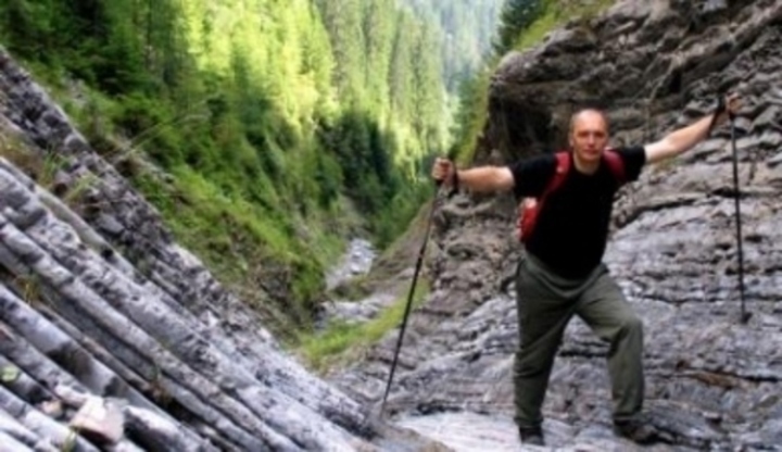 Muž jdoucí s holemi do kopce mezi skalami 