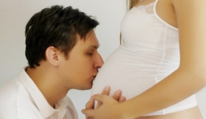 Muž líbající bříško své ženy 