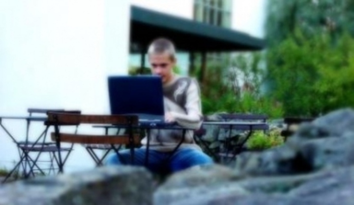 Chlapec sedící u notebooku v přírodě