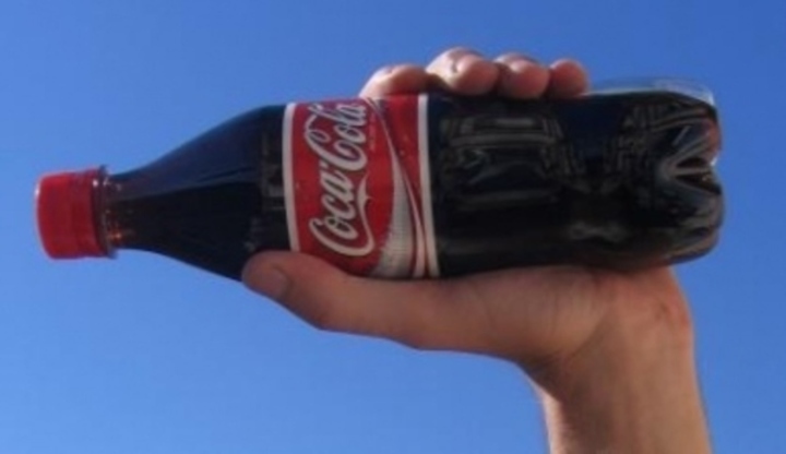 Ruka držící plastovou láhev s coca colou 