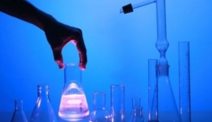 Ruka držící zkumavku v laboratoři 