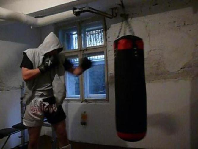 Muž v kapuci boxující do pytle 